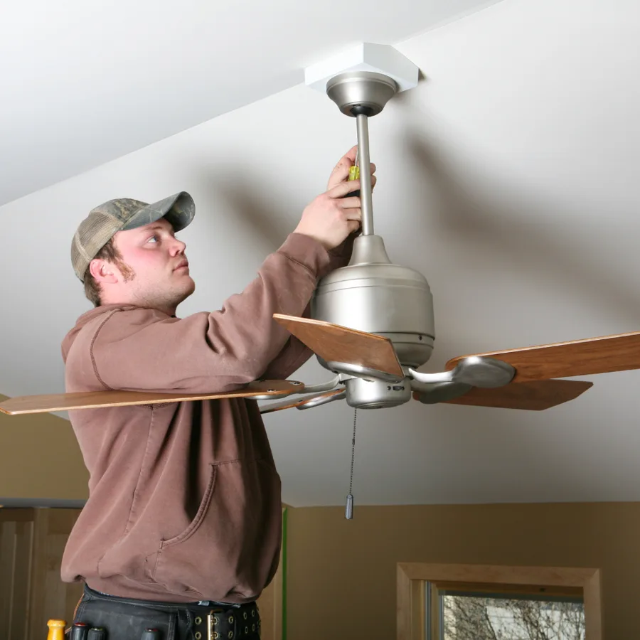 Technician adjusting the downrod of a ceiling fan mounted on a sloped ceiling