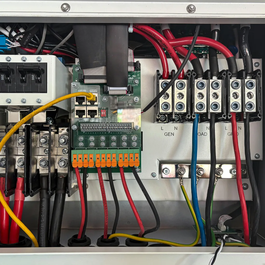 Interior of service equipment showing breakers, terminal blocks, and labeled generator, load, and grid connections