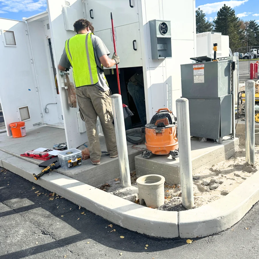 Electrical crew member working beside outdoor building equipment