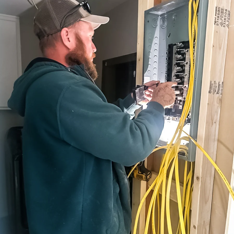 Electrician working on electrical panel wiring with yellow cables