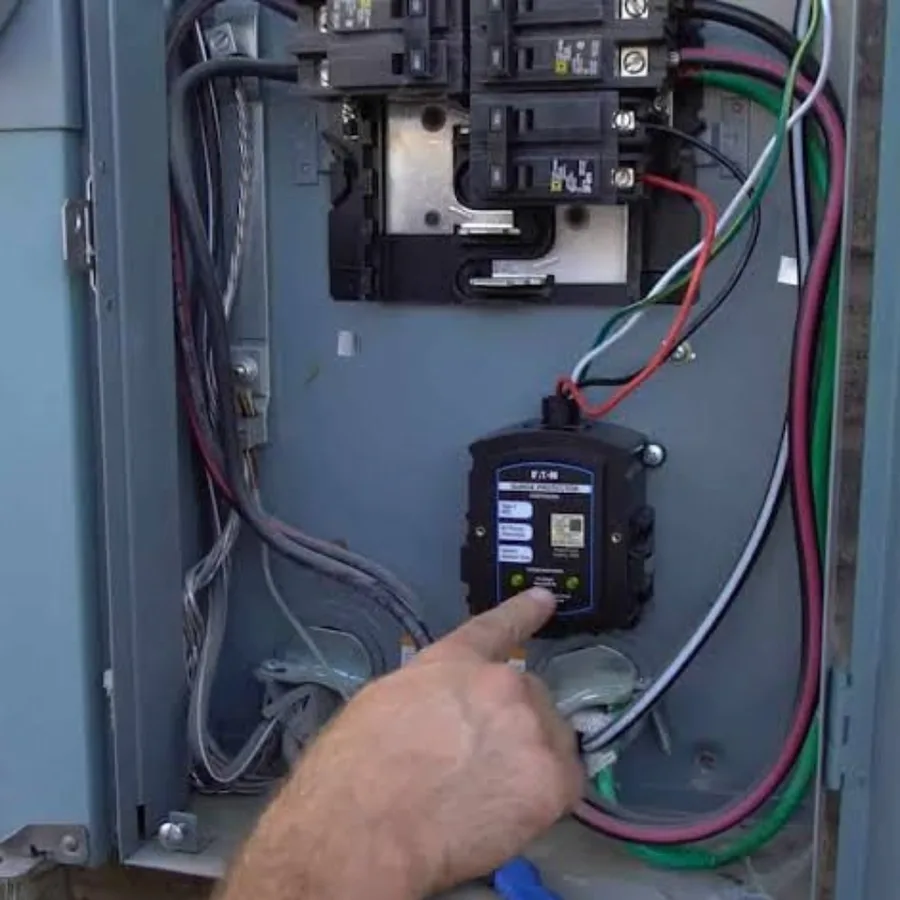 Hand pointing to the status indicator lights on a surge protective device inside a panel enclosure