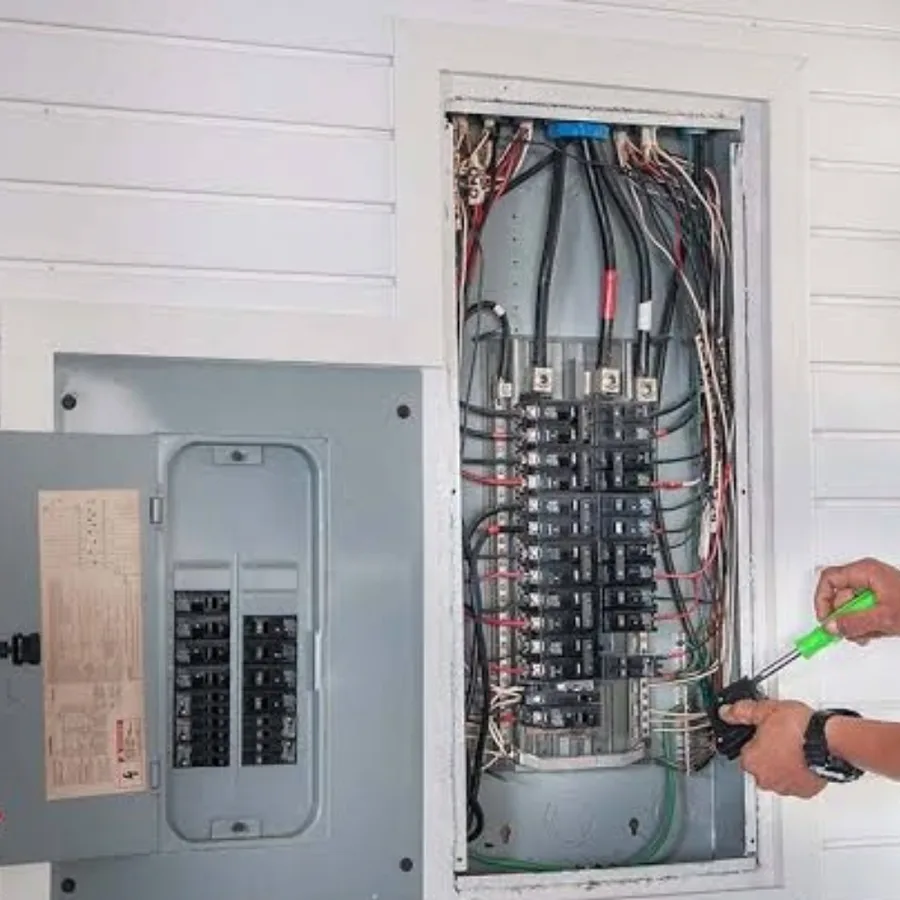 Electrician using a screwdriver on breakers inside an open residential electrical panel